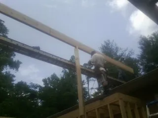 Carpenter setting a ridge beam over a new addition frame — Ice Dam Removal by Roofing Brothers in Midway City