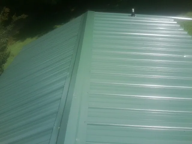 New green metal panels meeting at the ridge of a roof — Flat Roof Repair work by our crew in Midway City