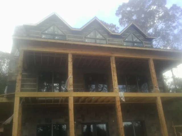 Dormers and porch framing on a large log home under construction — Roof Coating work by our crew in Midway City