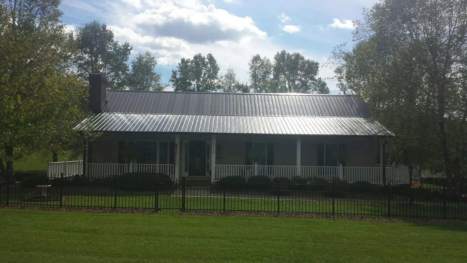 Gray metal roof on a brick ranch with a full width front porch — Gutter Guard Installation work by our crew in Midway City