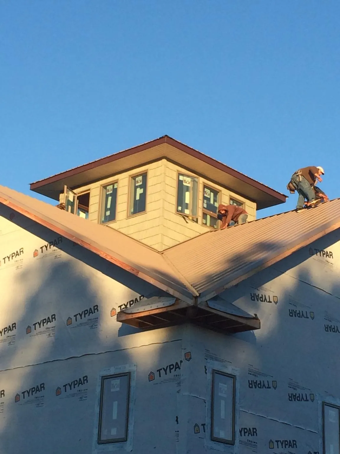 Roofers working around a rooftop cupola on a new metal roof at sunset — Roof Waterproofing in Midway City by Roofing Brothers